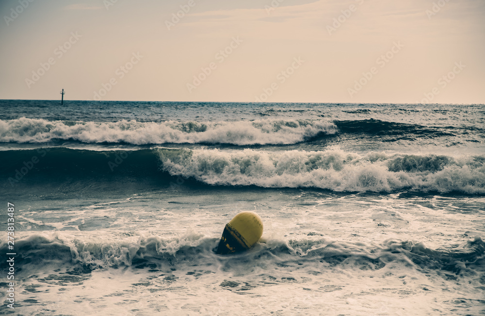 Buoy in the sea waves with foam. Empty beach. Summer vacations travel. Stormy ocean.