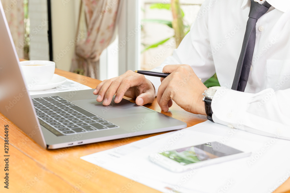 Businessman working on laptop with paperwork on table. Businessman working on laptop with paperwork on table.