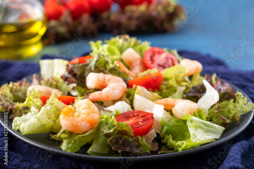 Tasty salad with shrimps, tomatoes and mixed greens on a plate. Healthy food. Diet food. Closeup