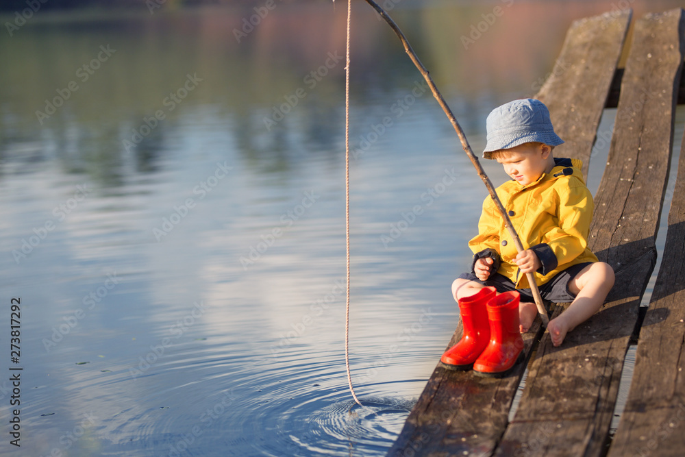A little boy fishing and wants to catch the biggest fish. Boy on wooden  dock with a fishing net Stock Photo