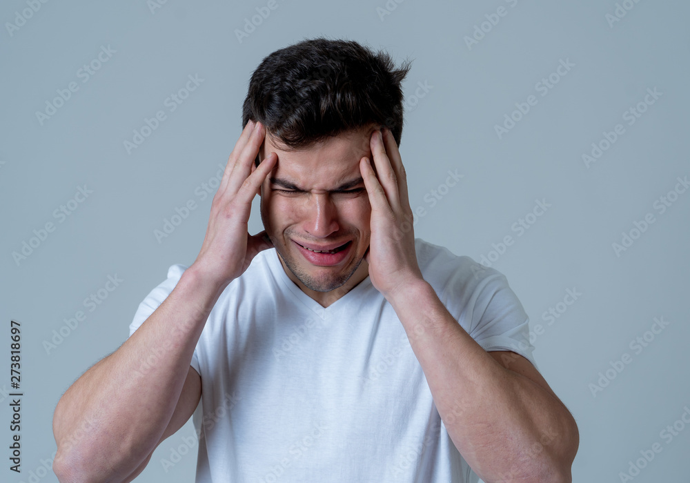 Naklejka premium Portrait of sad young man in strong emotional pain having headache and migraines