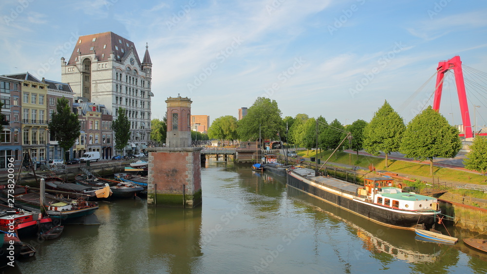 The White House (Witte Huis, Art Nouveau historical building) and historical houseboats viewed from Hertekade (near Oudehaven harbor) in Rotterdam, Netherlands, with Willemsbrug Bridge on the right
