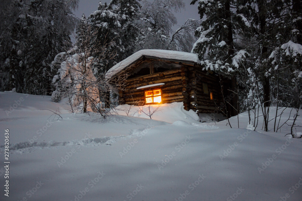 The light of a Christmas candle in the window of a lonely wooden log