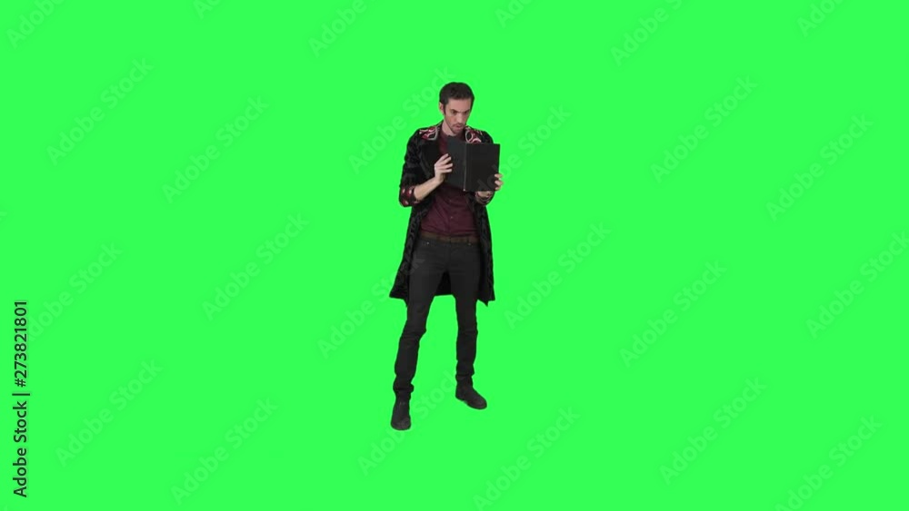 A magician performs a magic trick of a burning book over a green screen, A magician performs a magic trick of a burning book over a green screen,