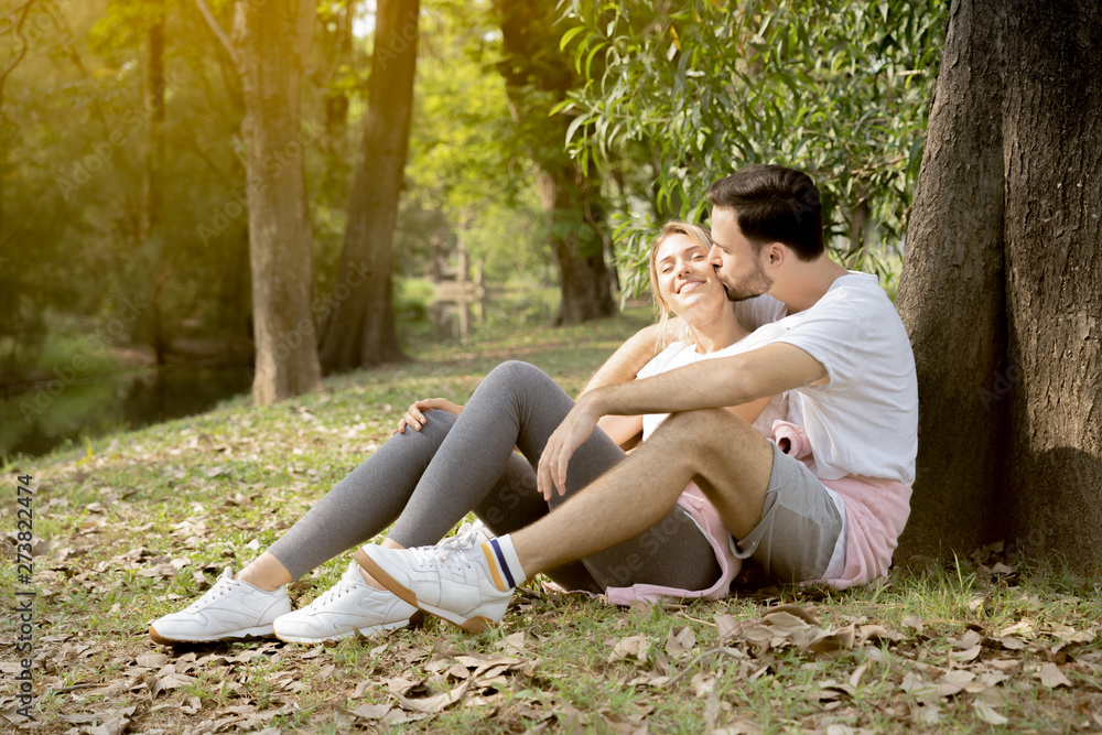 Portrait of a man kiss girlfriend under tree in park Portrait of a man kiss girlfriend under tree in park
