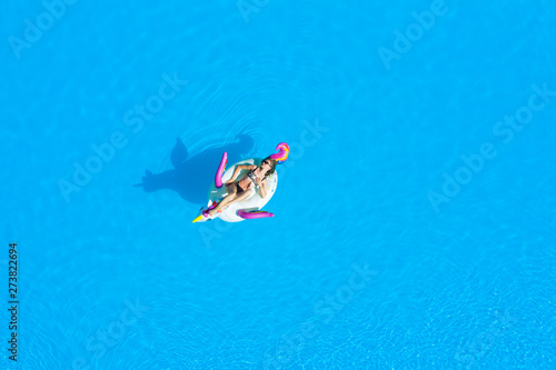 Top view of the pool with a girl in a swimsuit on an inflatable circle. Relaxing and tanning in the summer. © vfhnb12