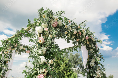 A festive chuppah decorated with fresh beautiful flowers for an outdoor wedding ceremony photo