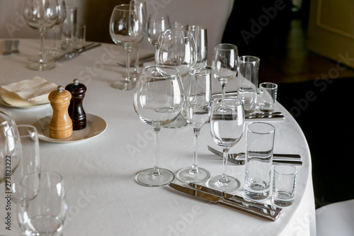 Beautiful table setting with crockery for a party, wedding reception or other festive event. Empty glassware and cutlery for catered event dinner. Horizontal photo © Sergei Shavin