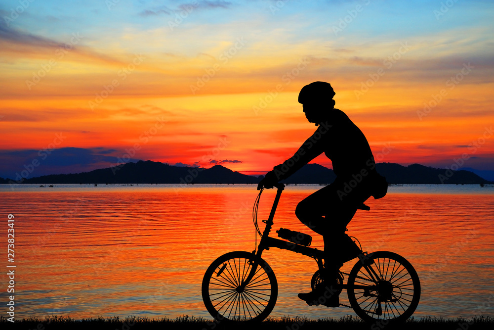 Obraz premium Silhouette man and bike relaxing on blurry sunrise sky background.