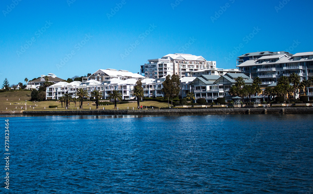 Harbourside condominium apartment housing with grass frontage, blue river against blue sky