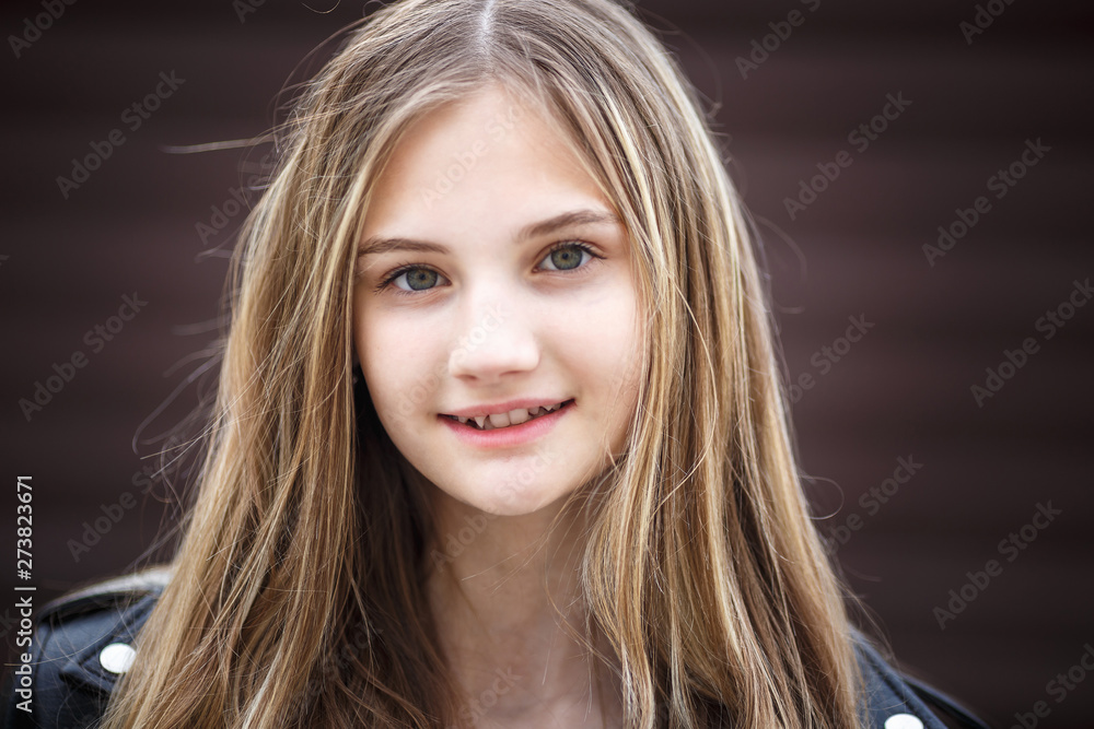 close-up portrait of little beautiful stylish kid girl against a brown striped wall close-up portrait of little beautiful stylish kid girl against a brown striped wall