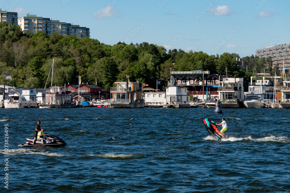 Stockholm, Sweden Jet skis in the lake in front of houseboats in the Solna suburb and Pampas Marina on a summer day.