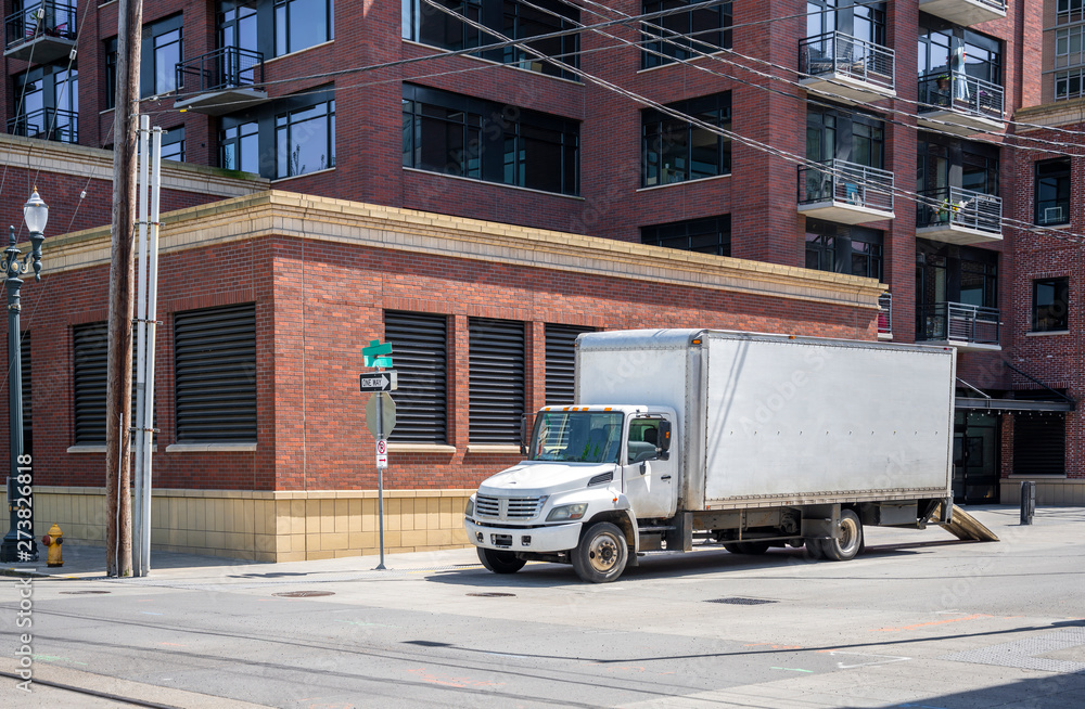 Compact small rid semi truck with box trailer standing in down town for loading moving goods