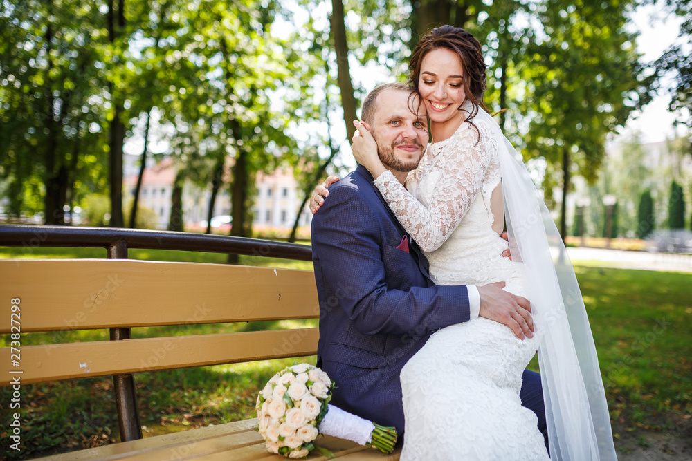 young couple newlyweds kissing on bench in city park young couple newlyweds kissing on bench in city park