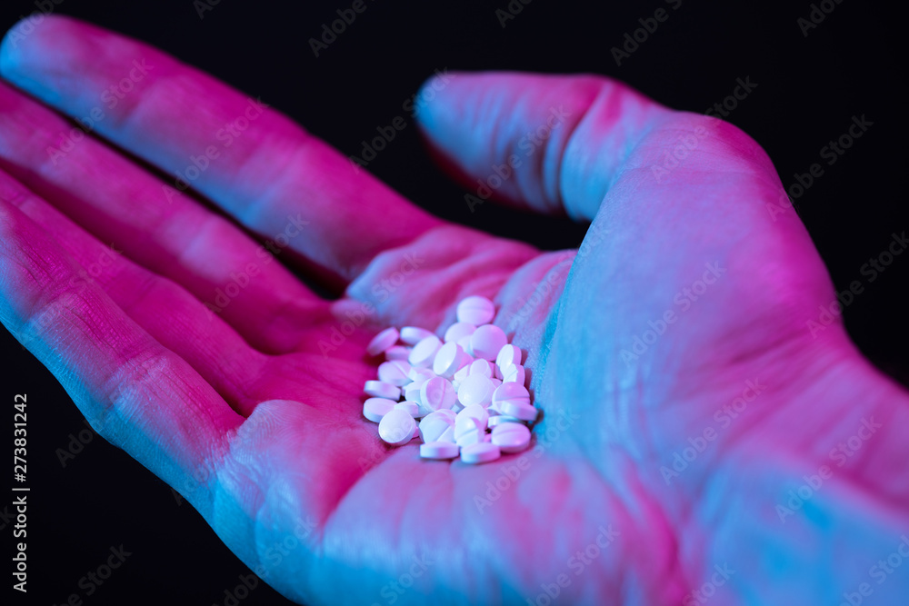 Pills in hand. Drug tablets in palm close-up on dark background Pills in hand. Drug tablets in palm close-up on dark background