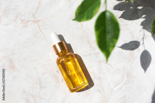 Serum in glass bottle on marble background. Aromatherapy oil, concept of natural cosmetic
