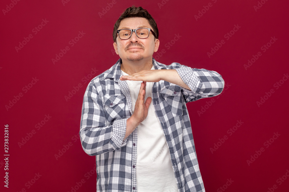 I need more time, please. Portrait of worried middle aged business man in casual checkered shirt and eyeglasses standing with time out gesture, pleading. studio shot, isolated on dark red background. I need more time, please. Portrait of worried middle aged business man in casual checkered shirt and eyeglasses standing with time out gesture, pleading. studio shot, isolated on dark red background.