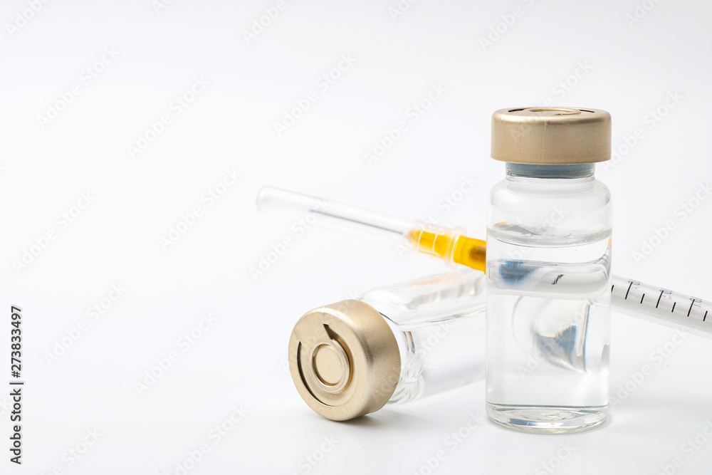 Vaccines, botulinum toxin and insulin ampules concept theme with glass vials with clear liquid next to a syringe and a hypodermic needle isolated on white background with copy space