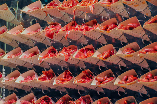 Envelopes with slices of red jamon on a glass stand. Background