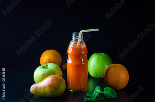 fresh juice from orange green apple with pears and carrots in a bottle with a straw front view on a black background