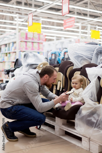 father with   small daughter choosing   car seat