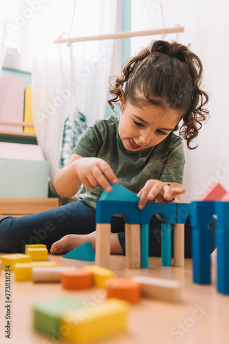 Obraz na plátně girl plays concentrated with building blocks