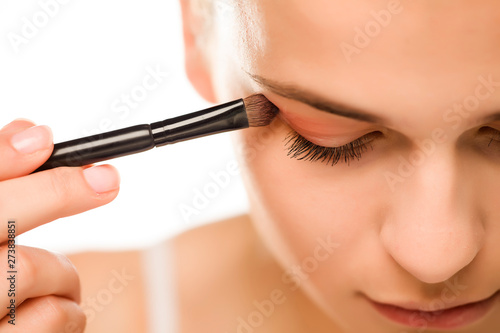 Young woman applying a eyeshadow with brush