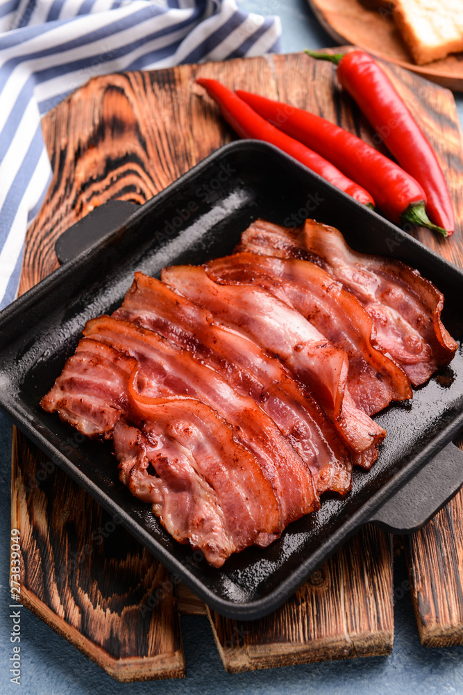 Frying pan with cooked bacon on table