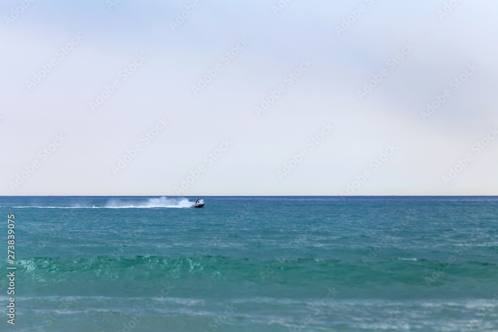 Seascape with racing on the waves jet ski parallel to the horizon.