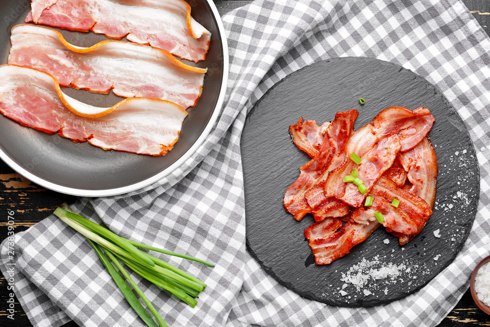 Raw and fried bacon on table