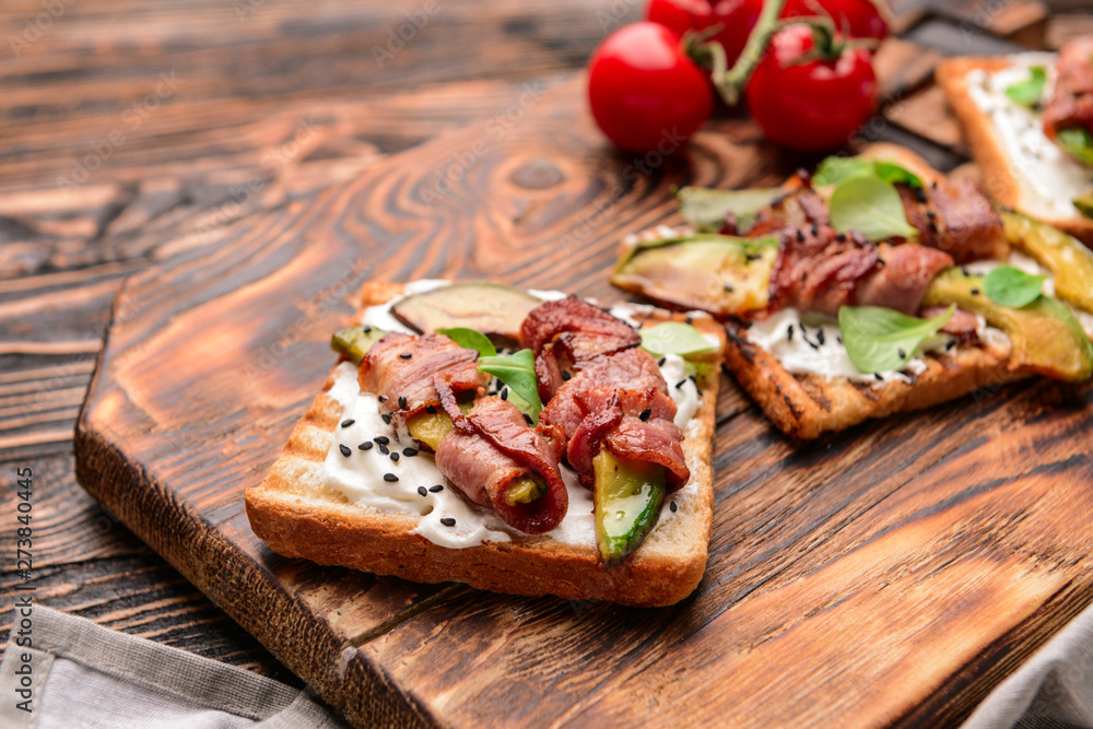 Tasty toasts with bacon on wooden board