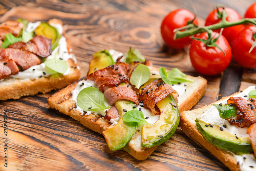 Tasty toasts with bacon on wooden board, closeup