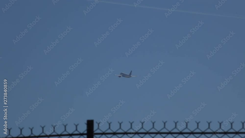 Plane taking off from the airport taken from behind a metal fence with a beautiful blue sky during the summer in Paris. Plane taking off from the airport taken from behind a metal fence with a beautiful blue sky during the summer in Paris.