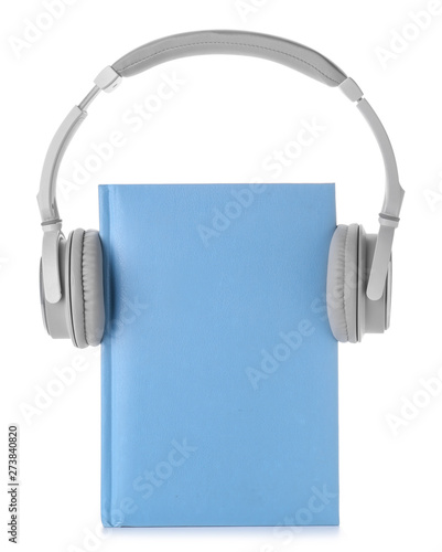 Book and modern headphones on white background. Concept of audiobook photo