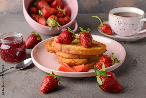 Plate with tasty French toasts and strawberry on grey table
