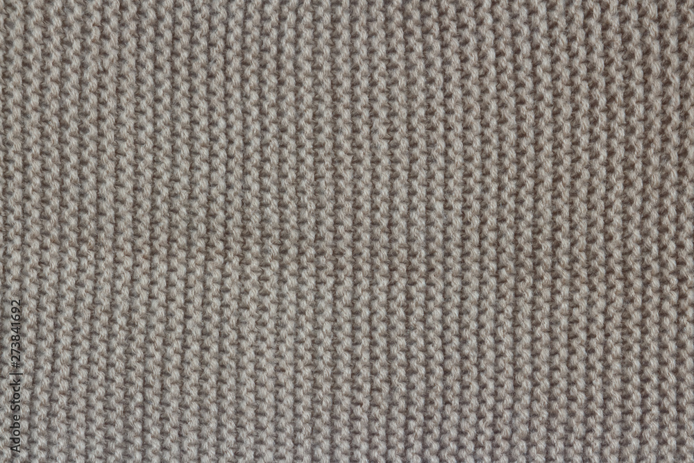 The texture of warm clothing for the autumn and winter season. Gray umber color knitted fabric. Machine binding. Close-up. The texture of warm clothing for the autumn and winter season. Gray umber color knitted fabric. Machine binding. Close-up.