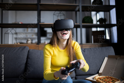 Cute girl plays the game on the console and eats pizza. VR experience