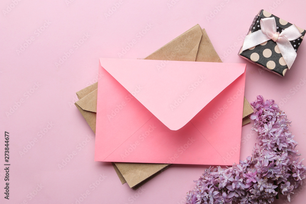 Pink envelope, lilac branch and gift box on a bright trendy pink background. top view