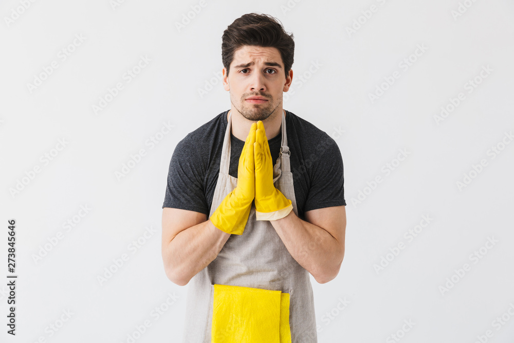 Sad young houseman househusband isolated over white wall background make please hopeful help gesture. Sad young houseman househusband isolated over white wall background make please hopeful help gesture.