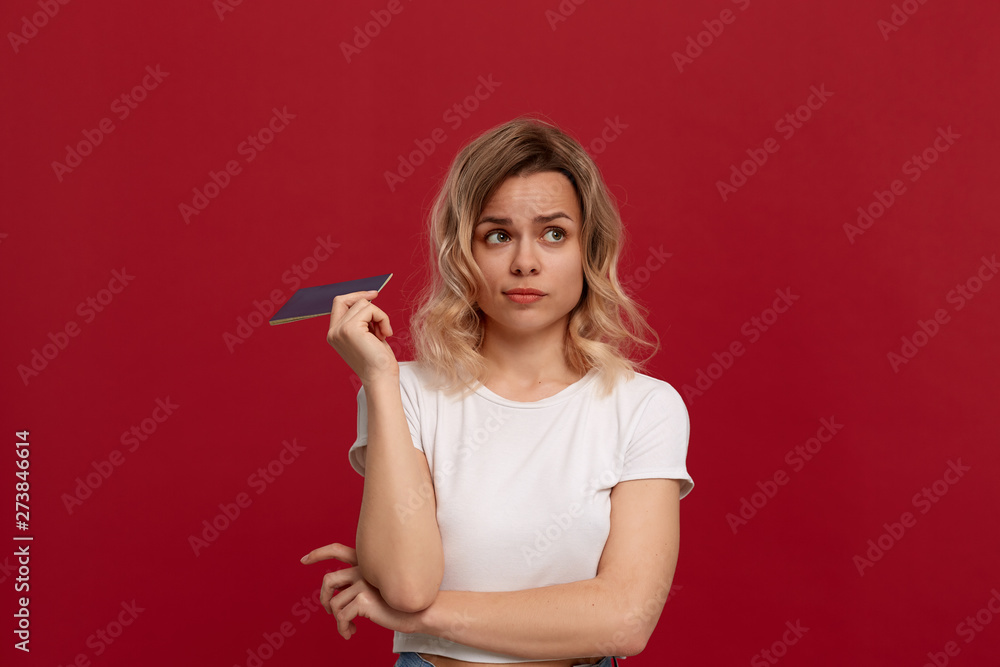 Portrait of a beautiful girl with curly blond hair dressed in a white t-shirt standing on a red background. Portrait of a beautiful girl with curly blond hair dressed in a white t-shirt standing on a red background.