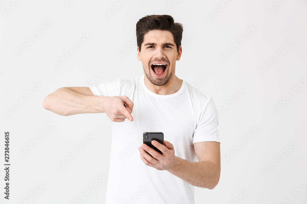 Excited happy young man posing isolated over white wall background using mobile phone. Excited happy young man posing isolated over white wall background using mobile phone.