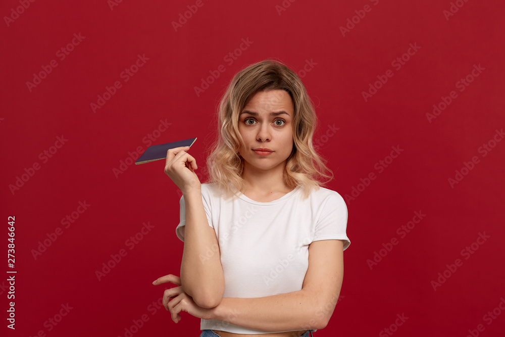 Portrait of a beautiful girl with curly blond hair dressed in a white t-shirt standing on a red background. Portrait of a beautiful girl with curly blond hair dressed in a white t-shirt standing on a red background.