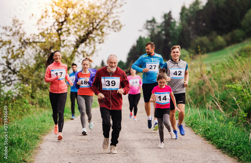 Large group of multi generation people running a race competition in nature.