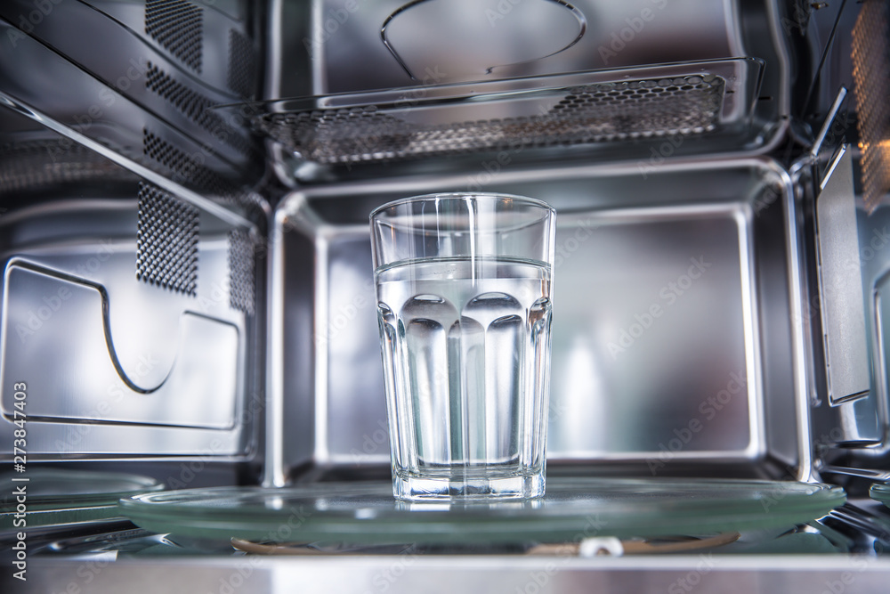 Inside view of new clean staniless, microwave oven with a cup of pure water Inside view of new clean staniless, microwave oven with a cup of pure water