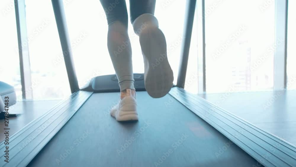 Woman running on treadmill machine in gym Woman running on treadmill machine in gym