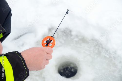 Winter fishing on ice. Man jiggling bait in an ice hole. Relaxin