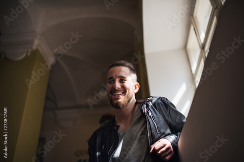 A low-angle portrait of young man standing indoors in a corridor.