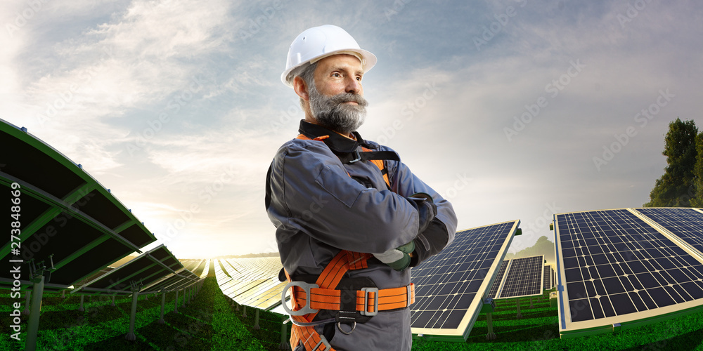 Happy engineer feel success after good work. He standing near solar station and looking beautiful sunset landscape Happy engineer feel success after good work. He standing near solar station and looking beautiful sunset landscape