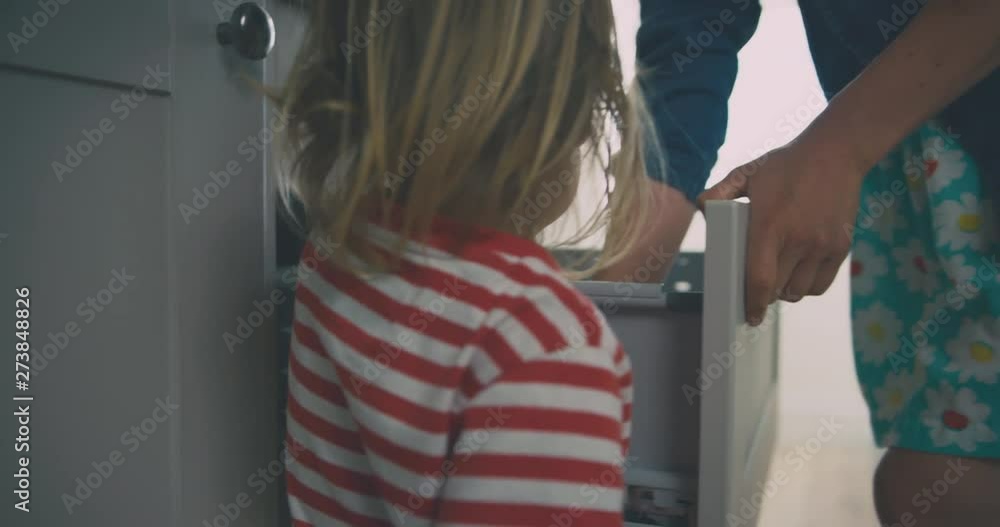 Young mother and toddler getting spoon from drawer Young mother and toddler getting spoon from drawer