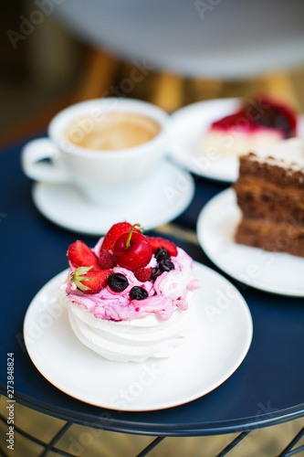 A cup of coffee and testy deserts on table in cafe.